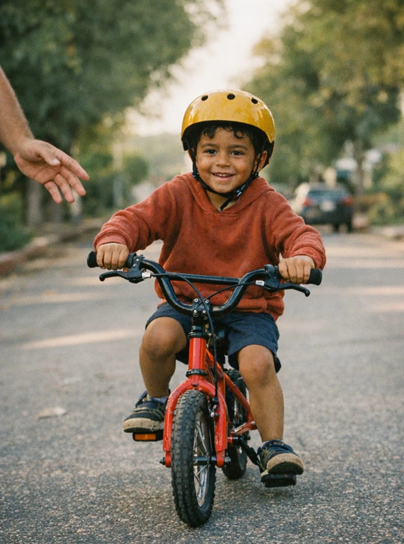 Ezra riding his red bicycle while his dad runs beside him